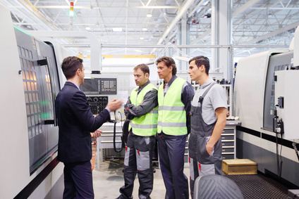 Manager and workers at plant near CNC machines